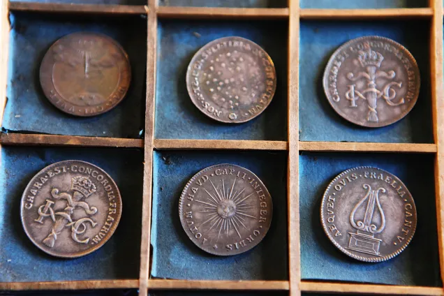 LUHM Myntkabinettet.jpg Sex stycken historiska mynt med bronsfärg ligger i två rader i små fack med turkos, sliten tygbakgrund