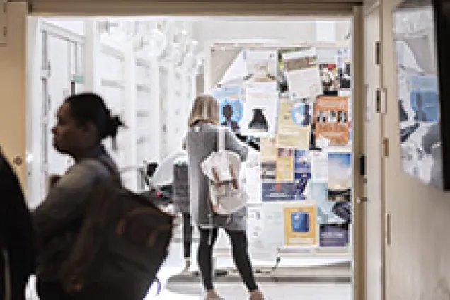 Student framför en anslagstavla i universitetets lokaler.