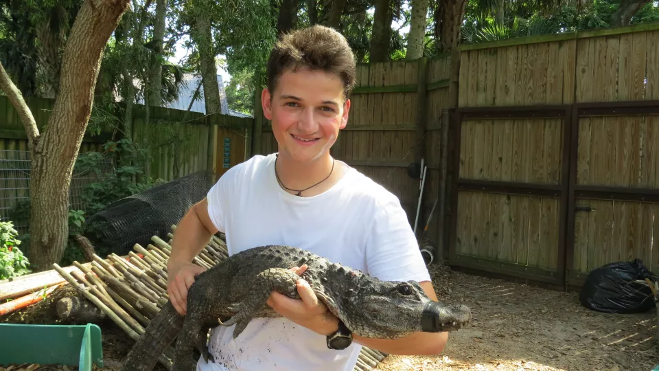 Stephan Reber håller en liten alligator i famnen