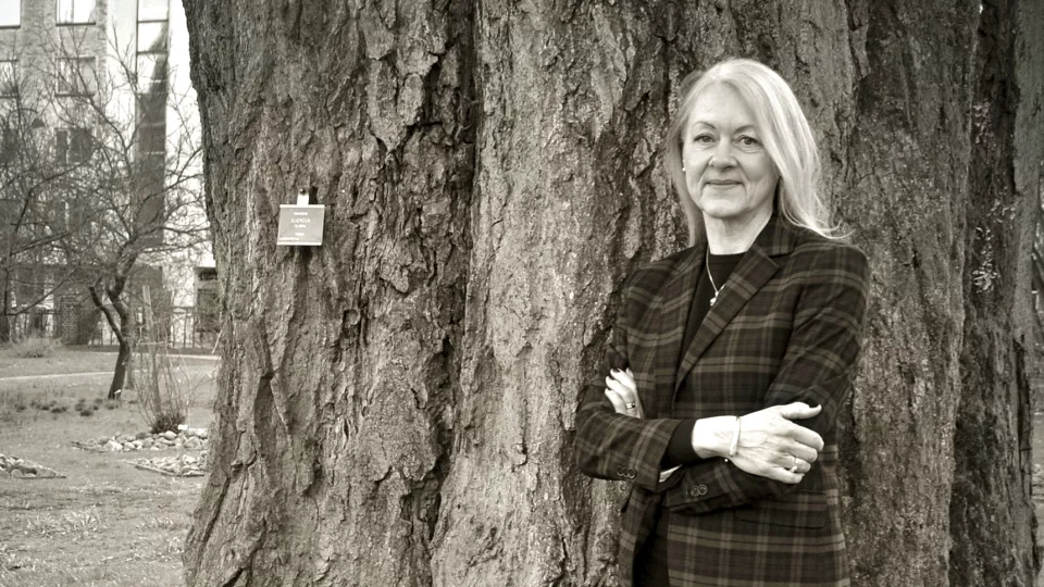 Kvinna fotograferad framför ett träd. Foto.
