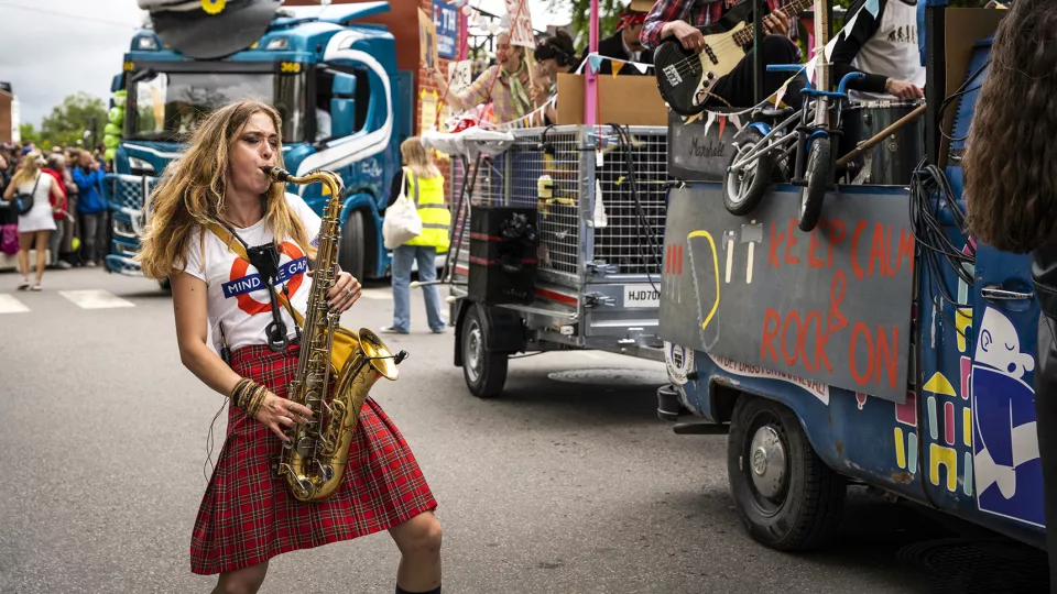 Kvinna spelar saxofon i karnevalståg.