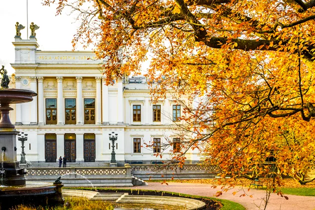 Universitetshuset med höstlöv på träden. Foto.