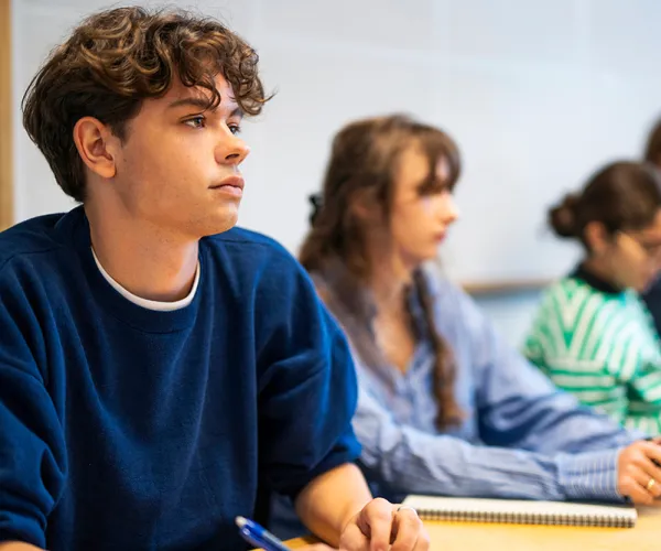Student lyssnar och antecknar. Foto.