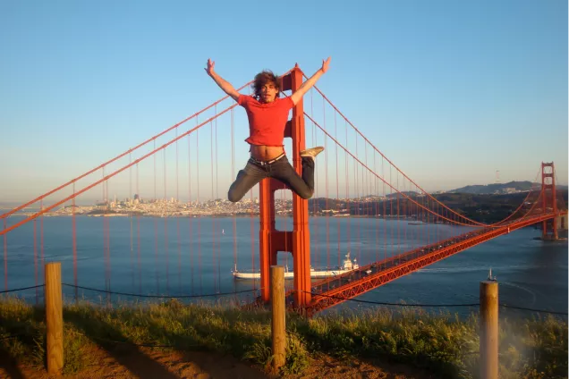 Student tar glädjeskutt framför Golden Gate. Foto.