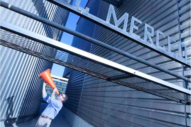 Lärare talar i megafon på Merced campus. Foto.