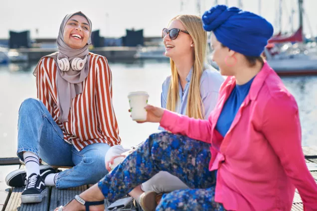 Tre kvinnliga studenter sitter vid vattnet i Helsingborg en solig sommardag. Fotograf Johan Persson. 