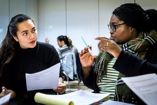 Två studenter diskuterar en artikel. Bilden är tagen i ett klassrum. Foto Kennet Ruona.