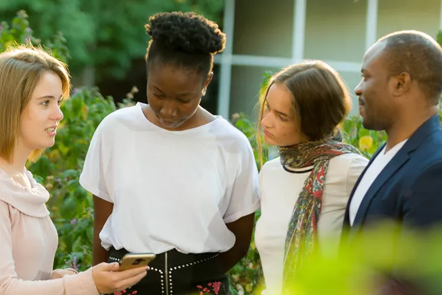 Internationella studenter diskuterar i grönska. Foto.