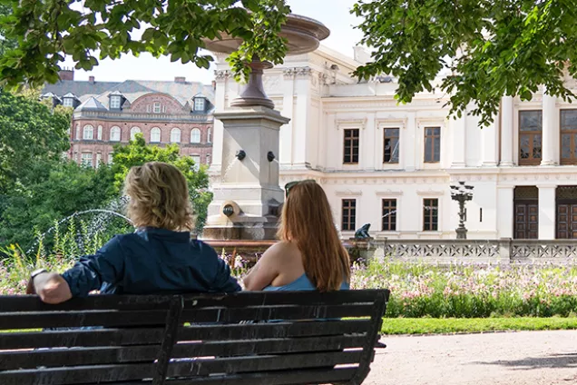 Studenter på bänk i Lundagård. Foto.