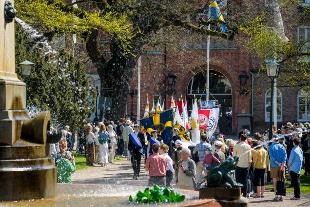_DSC8724©Ruona 24.jpg Bild på fanborgen som tågar förbi fontänen mot Universitetshuset vid rektorsuppvaktningen.