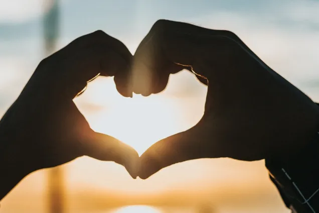 Valentin_foto_unsplash_SMALL-new.jpg Ett hjärta gjort av händer mot solnedgång. Foto.