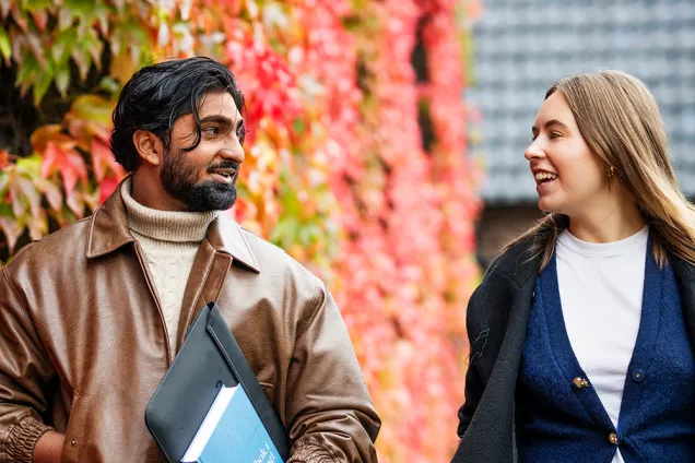 Två glada studenter på höstpromenad. Foto.