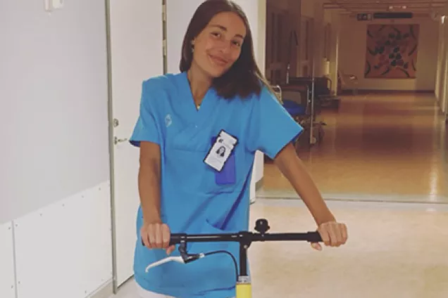 Läkarstudenten Isabella står i läkarrock på en sparkcykel nere i kulverterna på sjukhuset.