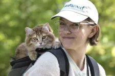 Katt sitter på en kvinnas ryggsäck. Foto