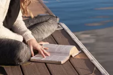 Kvinna läser på en brygga. Foto.