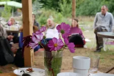 Flowers in a vase on the table with people sitting in the background. Photo.
