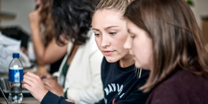 Två kvinnliga studenter pluggar tillsammans. 