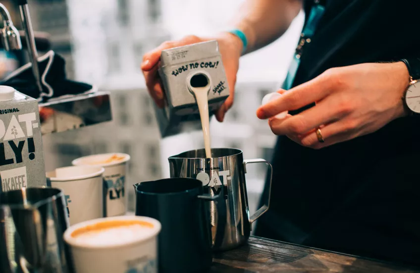 Person häller upp Oatly havredryck i kaffe.  Foto: Oatly pressbild.