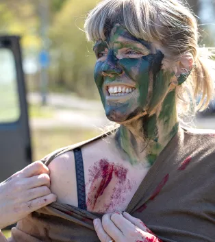Grönmålad kvinna med blödande fusksår. Foto. 